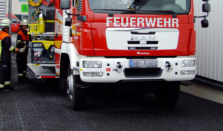 Feuerwehrauto steht auf einer mit dunklem Splitt befüllten ECORASTER Fläche.