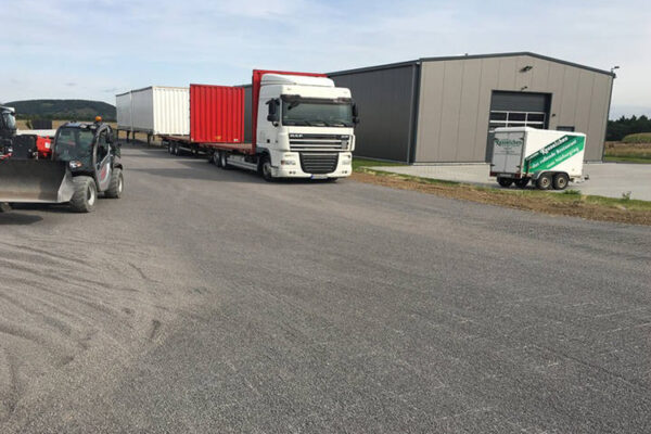 Logistik- und Lagerfläche mit parkenden LKWs auf ECORASTER Bodengittern, die mit Schotter befüllt sind