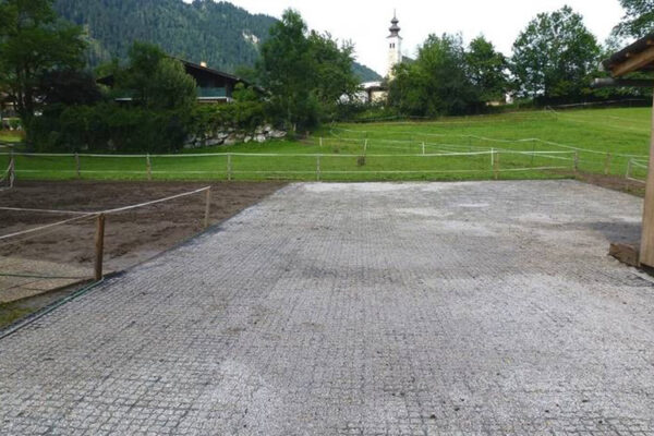 Mit Kies befüllte ECORASTER Bodengitter als Paddock und Kirche und Landschaft im Hintergrund.