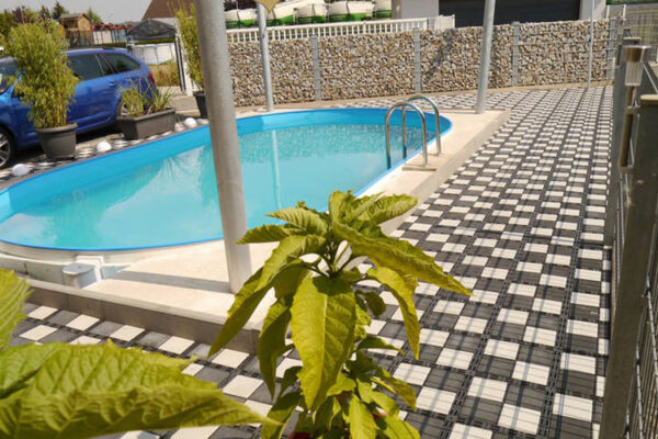 Poolbereich mit Planzen und mit ECORASTER Bloxx Fläche in Schachbrettmuster