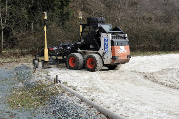 Maschine auf Reitplatz mit Büschen im Hintergrund