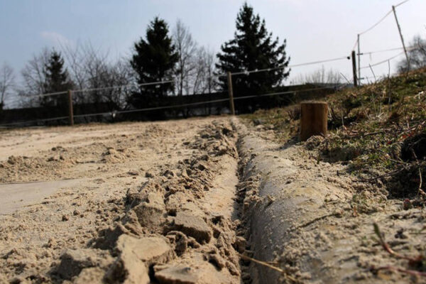 Nahaufnahme der holzigen Randeinfassung eines Reitplatzes mit Sand