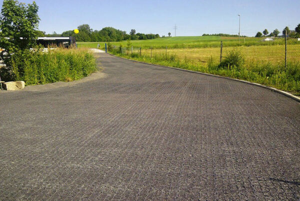 Mit Splitt verfüllte Fläche einer Einfahrt, im Hintergrund grüne Landschaft und Bäume