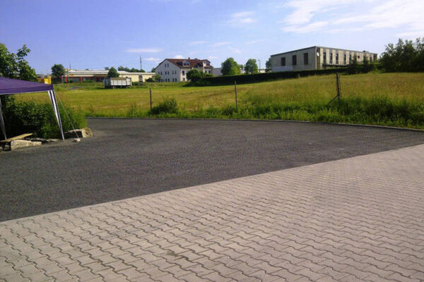 ECORASTER mit dunklem Splitt verfüllt grenzt an Pflasterfläche