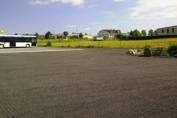Große Fläche von ECORASTER Mineral mit parkendem Bus und Häusern im Hintergrund