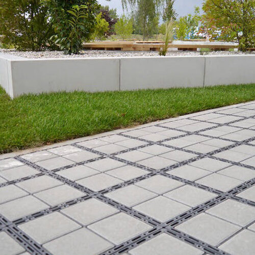 ECORASTER Bloxx Weg grentz an grüne Rasenfläche, im Hintergrund Büsche