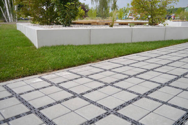 Zufahrt_Selb_05_800x500px ECORASTER Bloxx Weg grentz an grüne Rasenfläche, im Hintergrund Büsche