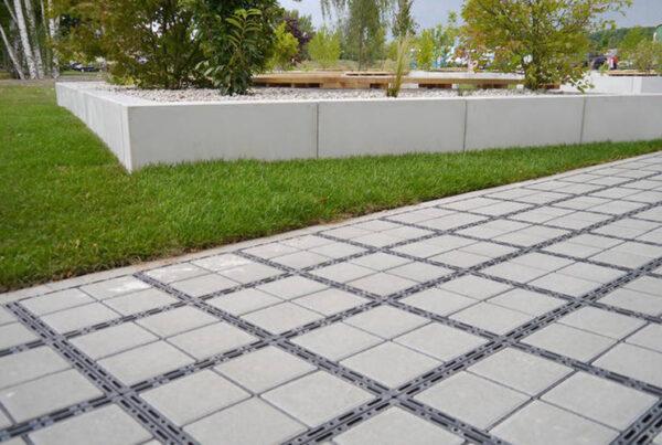 ECORASTER Bloxx Weg grentz an grüne Rasenfläche, im Hintergrund Büsche